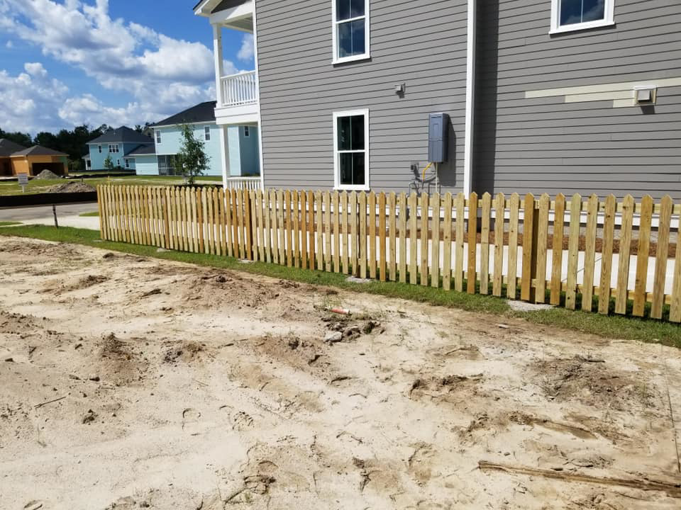 A newly installed wooden picket fence in a residential area by Frontline Fencing LLC in Summerville, SC.