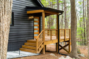 A newly constructed wooden porch and steps leading to the entrance of a house, built by Pro Finishes NC, LLC in Raleigh, NC.