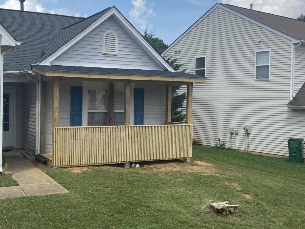 A newly constructed wooden porch with railings attached to a house by Donaldson & Company Construction in Charlotte, NC.