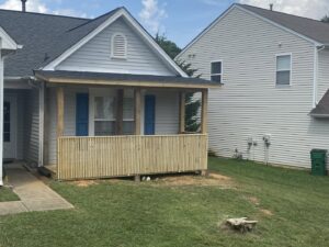 A newly constructed wooden porch with railings attached to a house by Donaldson & Company Construction in Charlotte, NC.