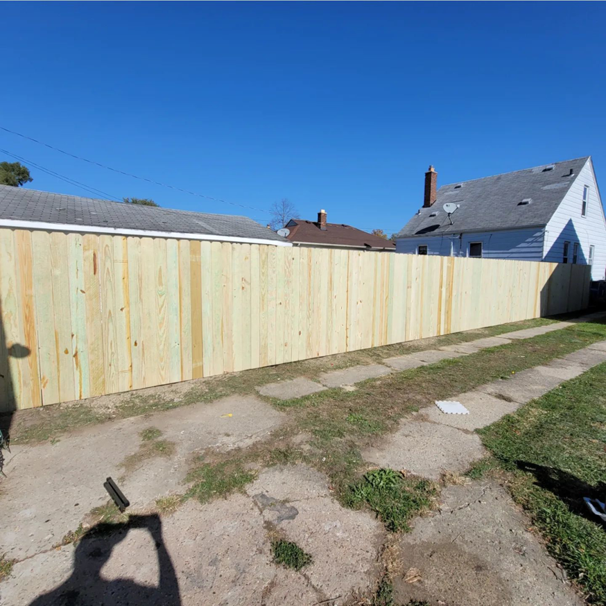 A newly installed wooden privacy fence in a backyard by Del Rey Properties LLC in Dearborn, MI.
