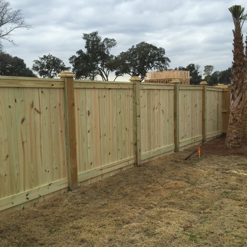 A newly installed wooden privacy fence featuring decorative post caps, completed by Frontline Fencing LLC in Summerville, SC.
