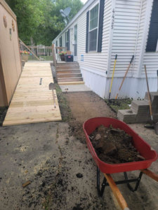 A new wooden ramp and pathway construction in progress with stacked pavers and a wheelbarrow, by Becker Services ND in West Fargo, ND.
