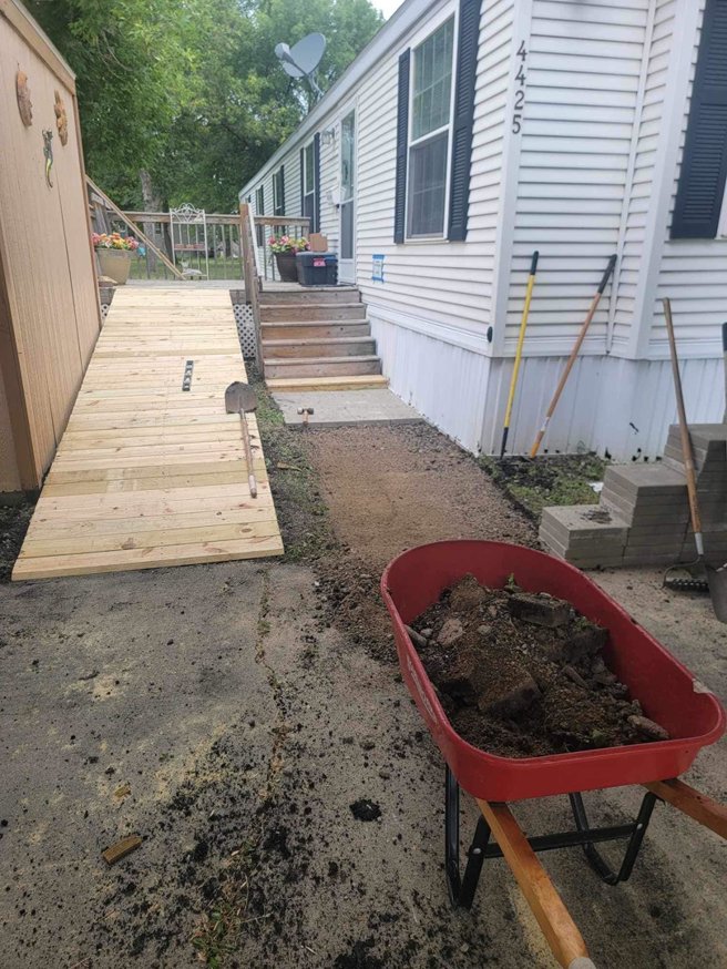 A new wooden ramp and pathway construction in progress with stacked pavers and a wheelbarrow, by Becker Services ND in West Fargo, ND.