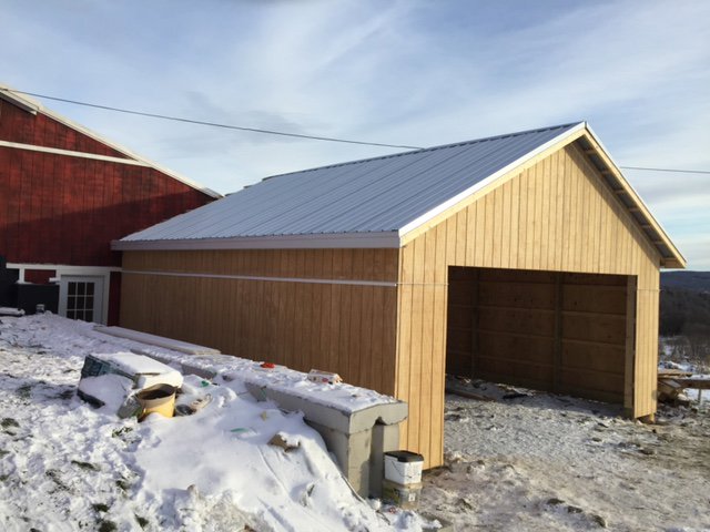 A newly constructed wooden shed or garage extension with a metal roof by Carl Gardner Contracting in Syracuse, NY.