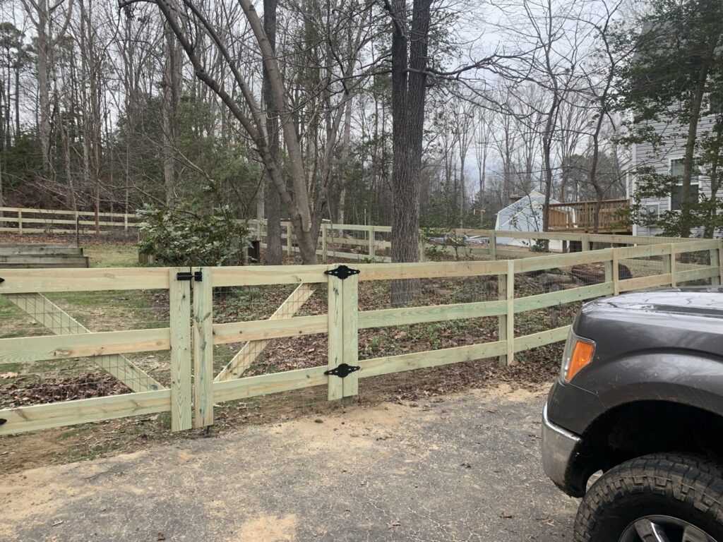 A newly installed wooden split rail fence with wire mesh and a double gate by Premier Fence Company in Glen Allen, VA.