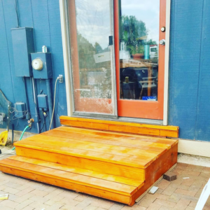 Newly installed wooden steps leading to a sliding glass door on a blue house by Steveson Enterprises, Inc. in Golden, CO.