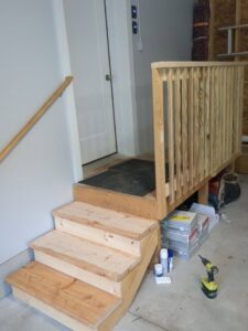 Newly built wooden steps and railing inside a garage by MB&E Home Improvement in Augusta, ME.