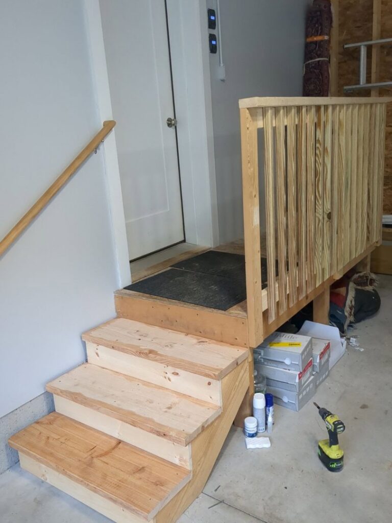 Newly built wooden steps and railing inside a garage by MB&E Home Improvement in Augusta, ME.