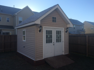 A newly built backyard storage shed with double doors and siding by RMG Construction in Chesapeake, VA.