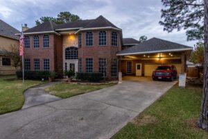 A newly built carport addition to a large brick house by Houston Home Improvements & Construction in Houston, TX