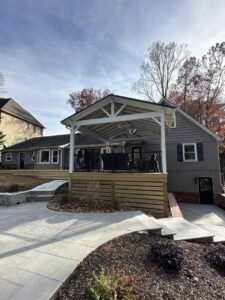 A newly built covered patio and deck area with a modern fence and fresh landscaping, a construction project by Picasso Poolscapes in Johns Creek, GA.