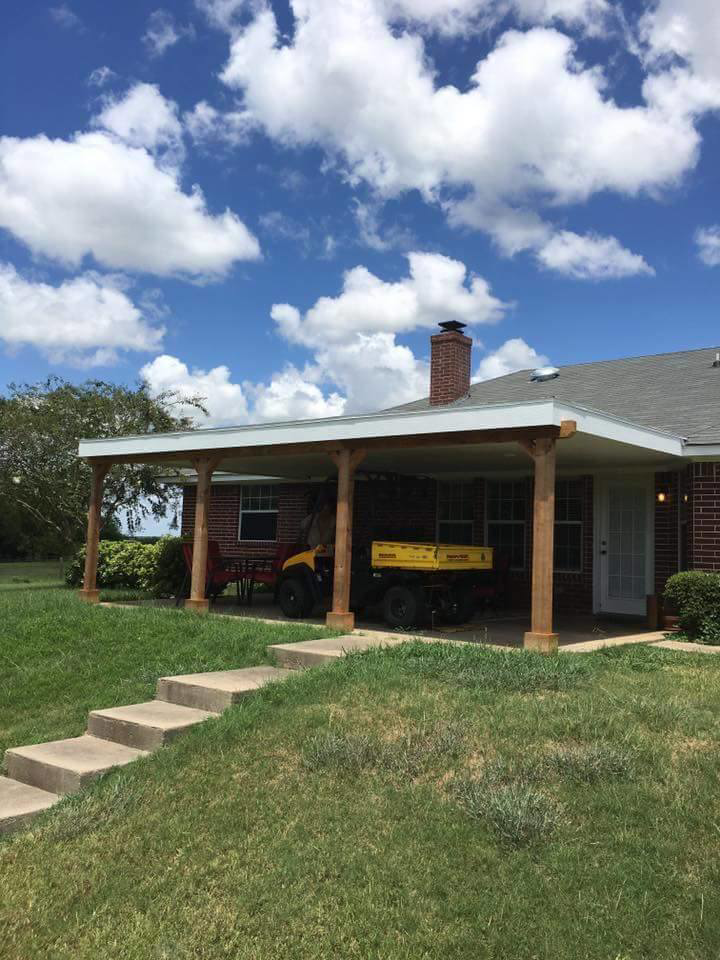 A newly built covered patio with wooden posts and a white roof by Whitehorn Construction in Austin, TX.