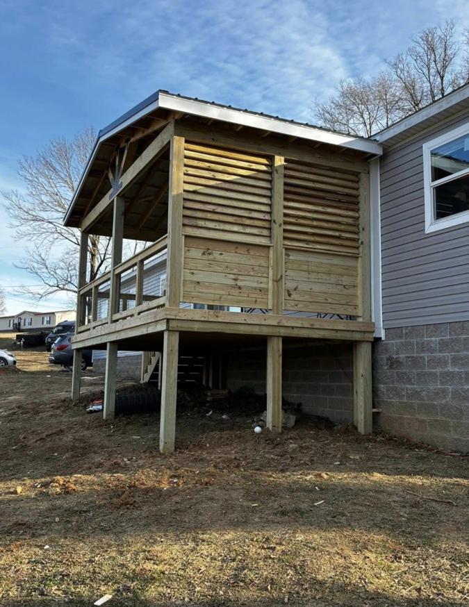 A newly constructed covered wooden porch and deck by Savage Home Builders in Hodgenville, KY