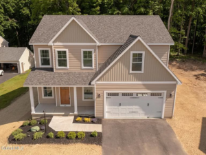 An aerial view of a newly built custom home with beige siding and a two-car garage by McDonald Custom Homes in Schenectady, NY.