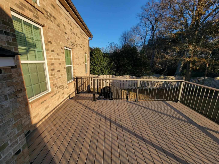 A newly built outdoor deck with modern railings next to a brick house by AccampoBros Home Solutions in Greenville, SC.