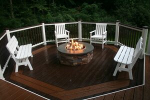 A newly built outdoor deck with a stone fire pit and white chairs by Santoro Home Improvements in Wallingford, CT.
