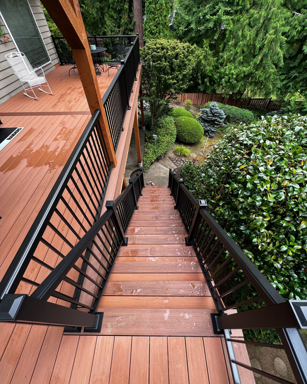 A view looking down newly built wooden deck stairs with black railings by Rosas Construction and Renovation in Dallas, TX.