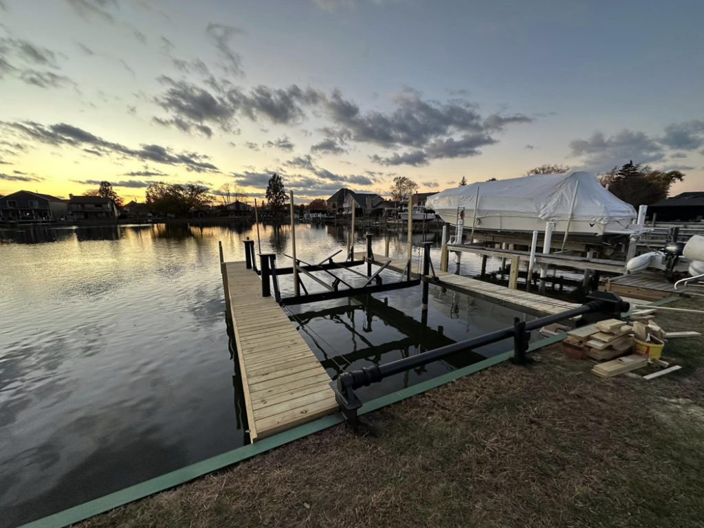 A newly built wooden dock and boat lift at sunset by TopNotch Remodeling & Restoration Service LLC in Warren, MI