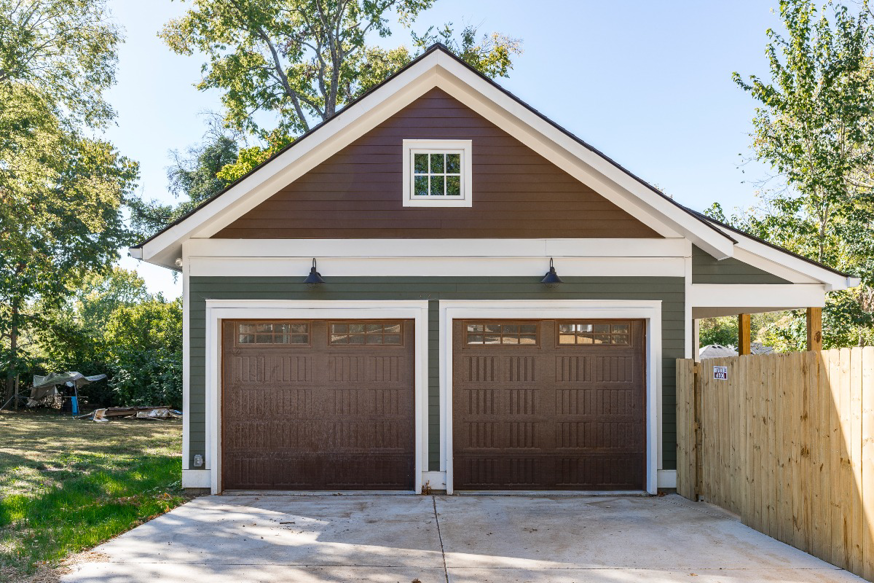 A newly built or renovated garage exterior with two brown garage doors and new siding by Nova Constructors in Nashville, TN.