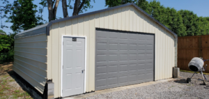 A newly constructed metal shed or garage with beige siding and a gray garage door by Walnut Bridge Construction in Knoxville, TN