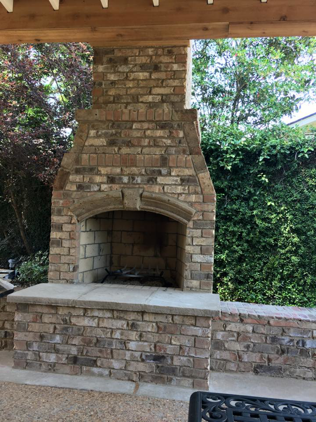 Newly built outdoor brick fireplace and patio area by Felipe Garcia Remodeling and Construction in Mobile, AL.