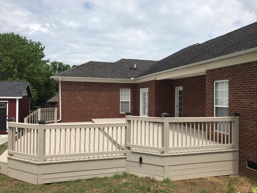 A spacious, newly built outdoor deck attached to a brick home by Heritage Design & Remodel in Raleigh, NC.