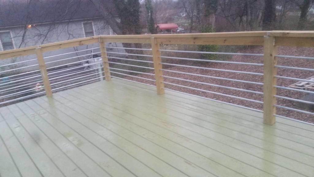 A newly built outdoor deck featuring modern metal cable railings and wooden posts by Big Idea Construction, LLC in Knoxville, TN.