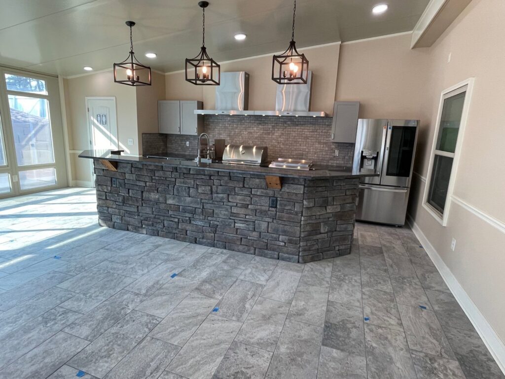 The interior of a newly built outdoor kitchen with a stone island by Four Seasons of River City in Columbus, GA.