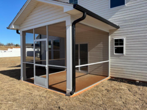 A newly built screened porch with a black gutter system attached to a white house by AccampoBros Home Solutions in Greenville, SC.