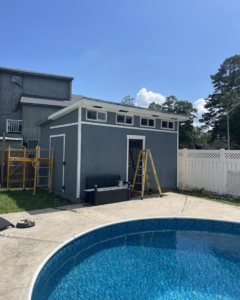 A newly built or renovated shed next to a swimming pool by Comeaux Home Services in Baton Rouge, LA.