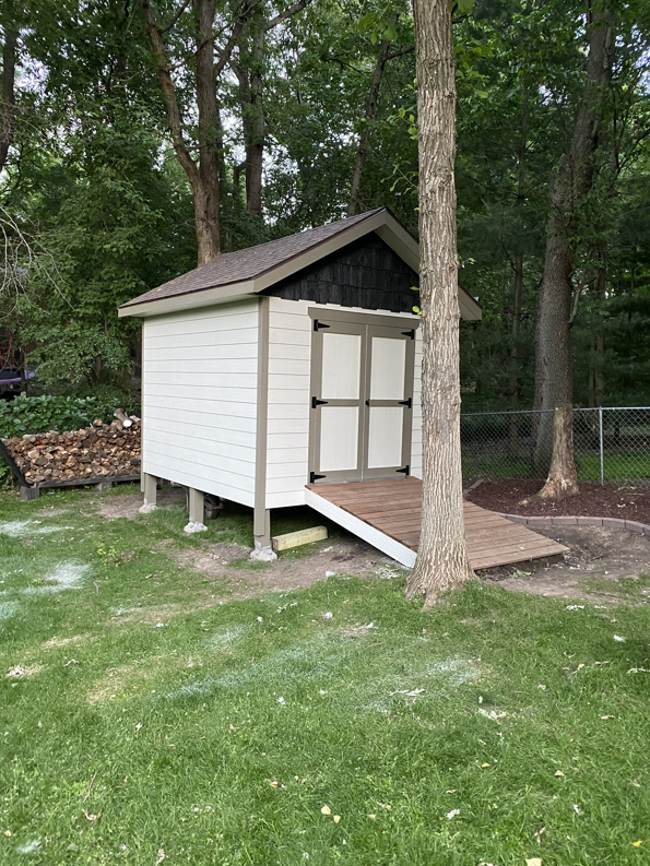 A newly built shed with a small wooden ramp in a backyard by Elde Contracting in Saint Paul, MN.