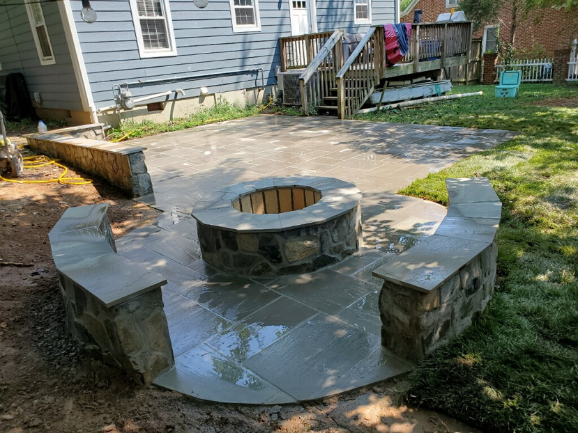 A newly built stone patio with a fire pit and curved seating walls by NOVA Construction Pro in Alexandria, VA.
