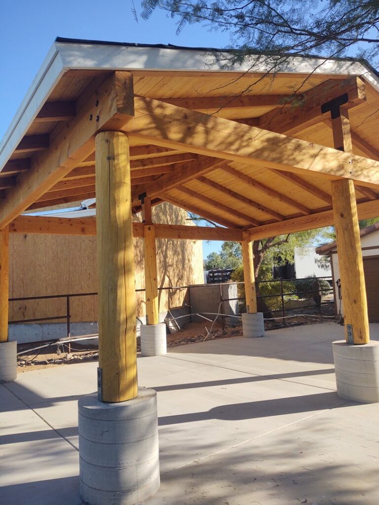 A newly built outdoor patio or pergola with large wooden beams and posts by AZ Framing and Remodeling in Peoria, AZ