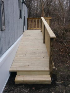A newly built wooden access ramp and small deck leading to a home by Home Solutions of Kansas City in Kansas City, MO
