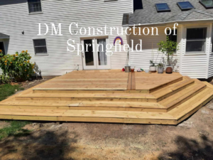 A newly built wooden deck with multiple steps leading to a house, constructed by DM Construction of Springfield in Springfield, IL.