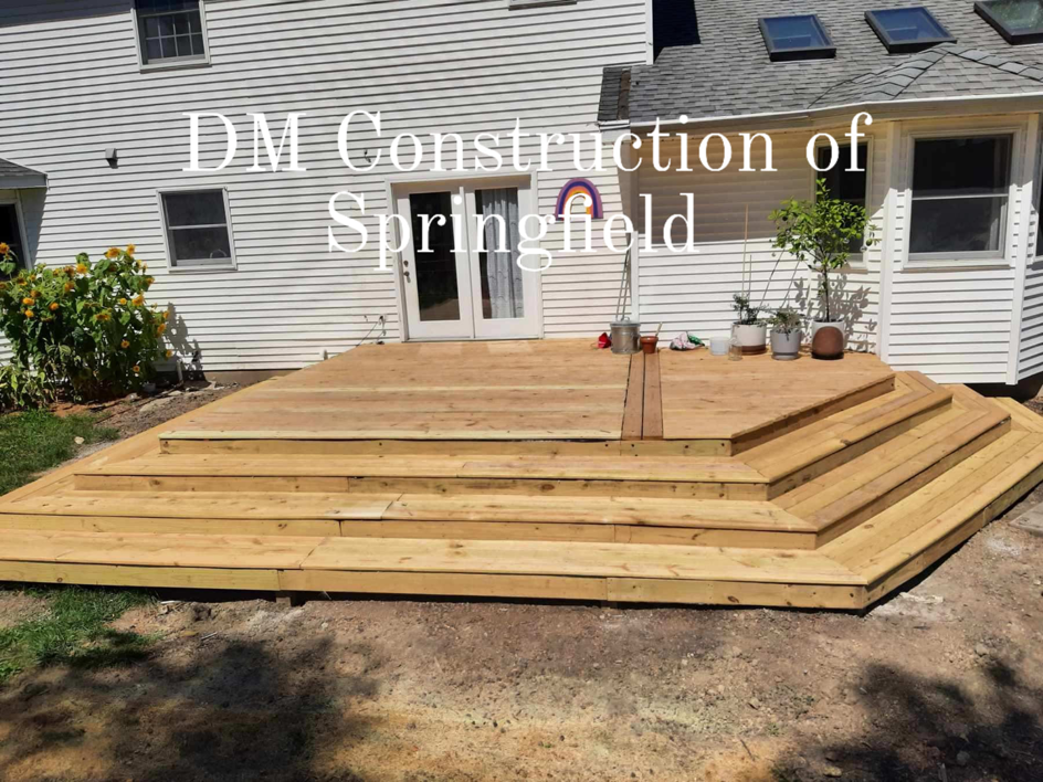 A newly built wooden deck with multiple steps leading to a house, constructed by DM Construction of Springfield in Springfield, IL.