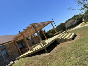 A newly built wooden deck with a pergola attached to a house by Jimenez services in Hawthorne, CA.