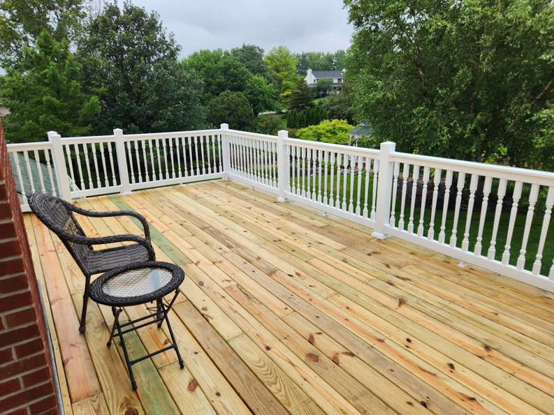 A newly built wooden deck with white railings and outdoor furniture by SG Service, LLC in Lincoln, NE