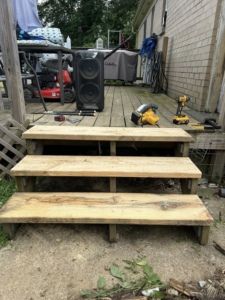 Newly built wooden deck stairs with construction tools on the deck, completed by A2 Construction in Louisville, KY.
