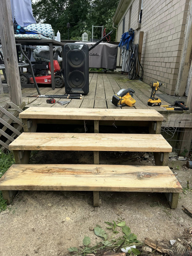 Newly built wooden deck stairs with construction tools on the deck, completed by A2 Construction in Louisville, KY.