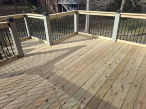 A newly built wooden deck surface with railings by American Renovation Llc in Fairplay, SC.