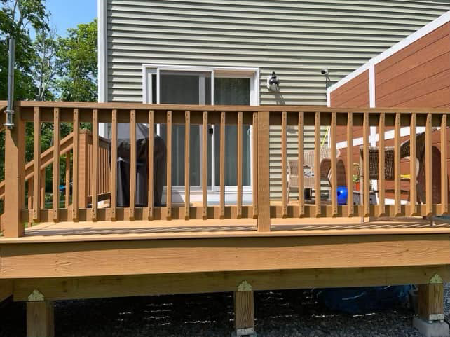 A newly built wooden deck with sturdy railings by Friendly Neighborhood Handyman in Uxbridge, MA.
