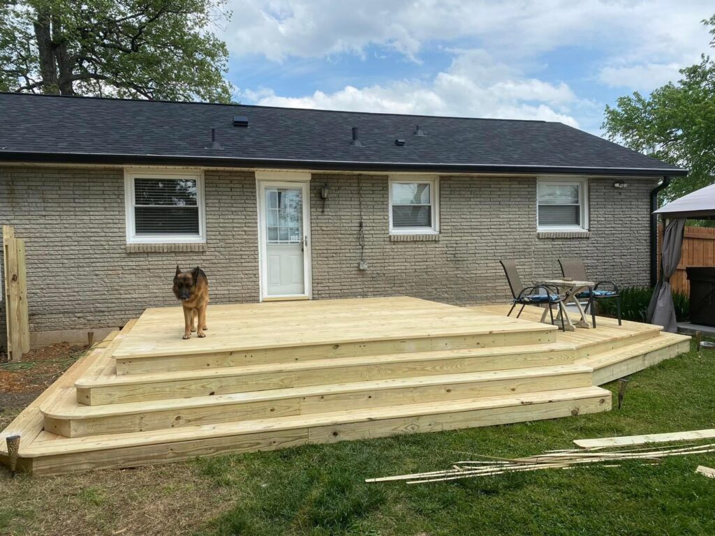 A newly built wooden deck with multiple steps extending from a brick house, completed by Richwood Remodeling & Outdoor in Nashville, TN.