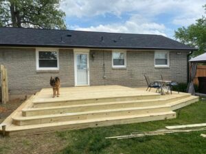 A newly built wooden deck with multiple steps extending from a brick house, completed by Richwood Remodeling & Outdoor in Nashville, TN.