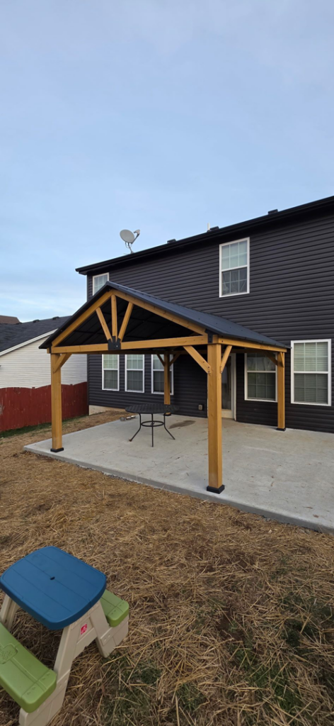 A newly built wooden patio cover with a dark roof, constructed by Luv-2-Build, LLC in Lexington, KY.