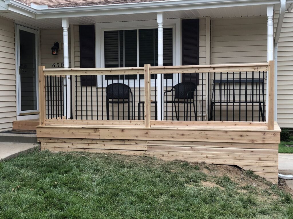 A newly built wooden porch with black metal railings in front of a house by E.L. Construction in Kansas City, MO.