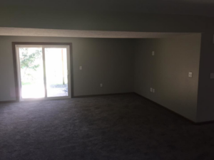A newly carpeted room with a sliding glass door installed by Kline Custom Homes and Remodelers in Canton, OH.