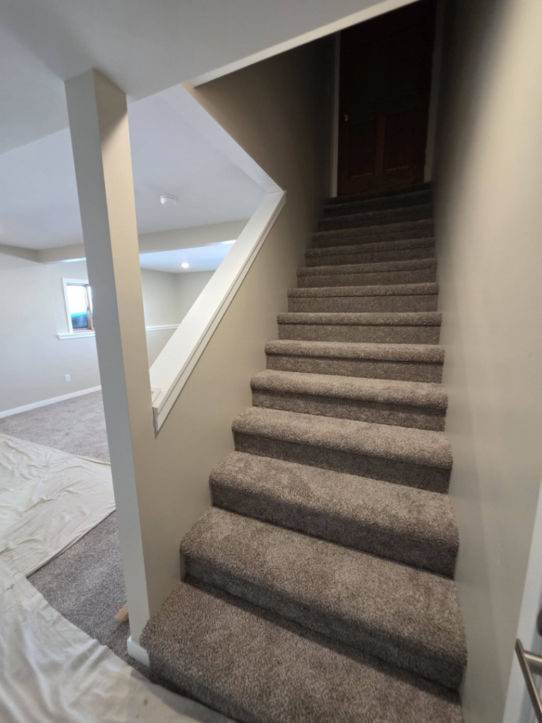 A newly carpeted staircase with a white railing and painted walls by Rosenthal Remodeling in Milton, WI.