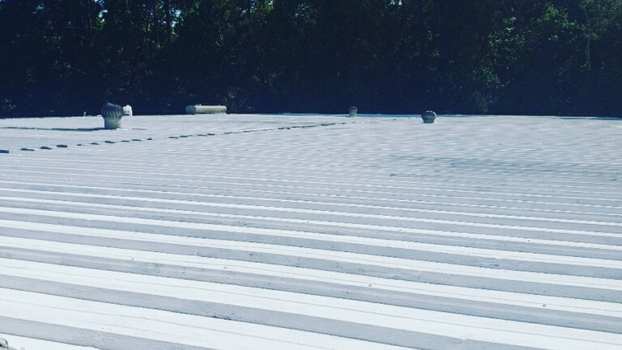 A newly coated, clean white commercial flat roof, showcasing a completed project by Charleston Roofs & Windows in North Charleston, SC.